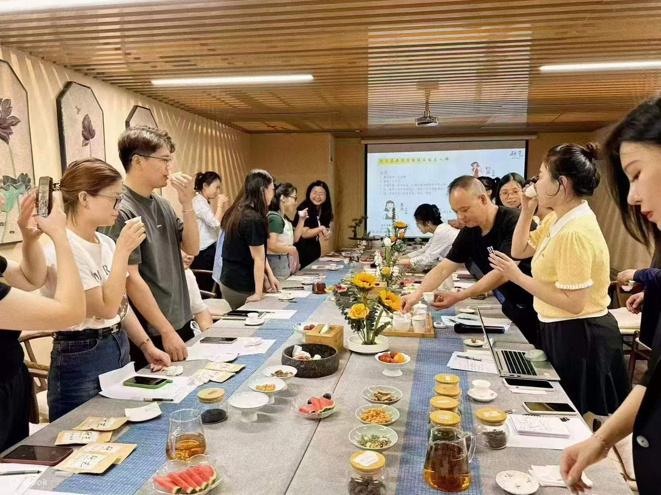 以茶会友的品鉴活动现场，众多茶友齐聚一堂，围绕长桌品鉴各类茶叶